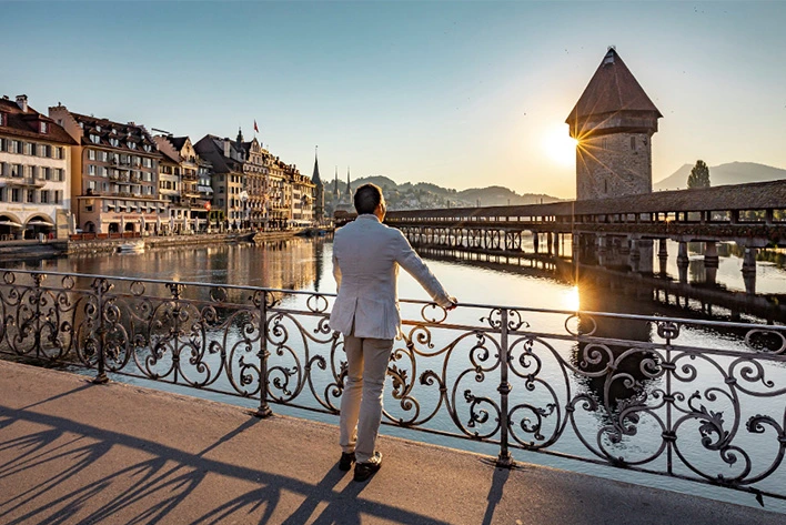 A person standing on Chapel bridge in Lucerne, Switzerland overlooking a body of water